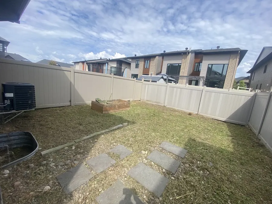 A fenced yard with stepping stones across the lawn